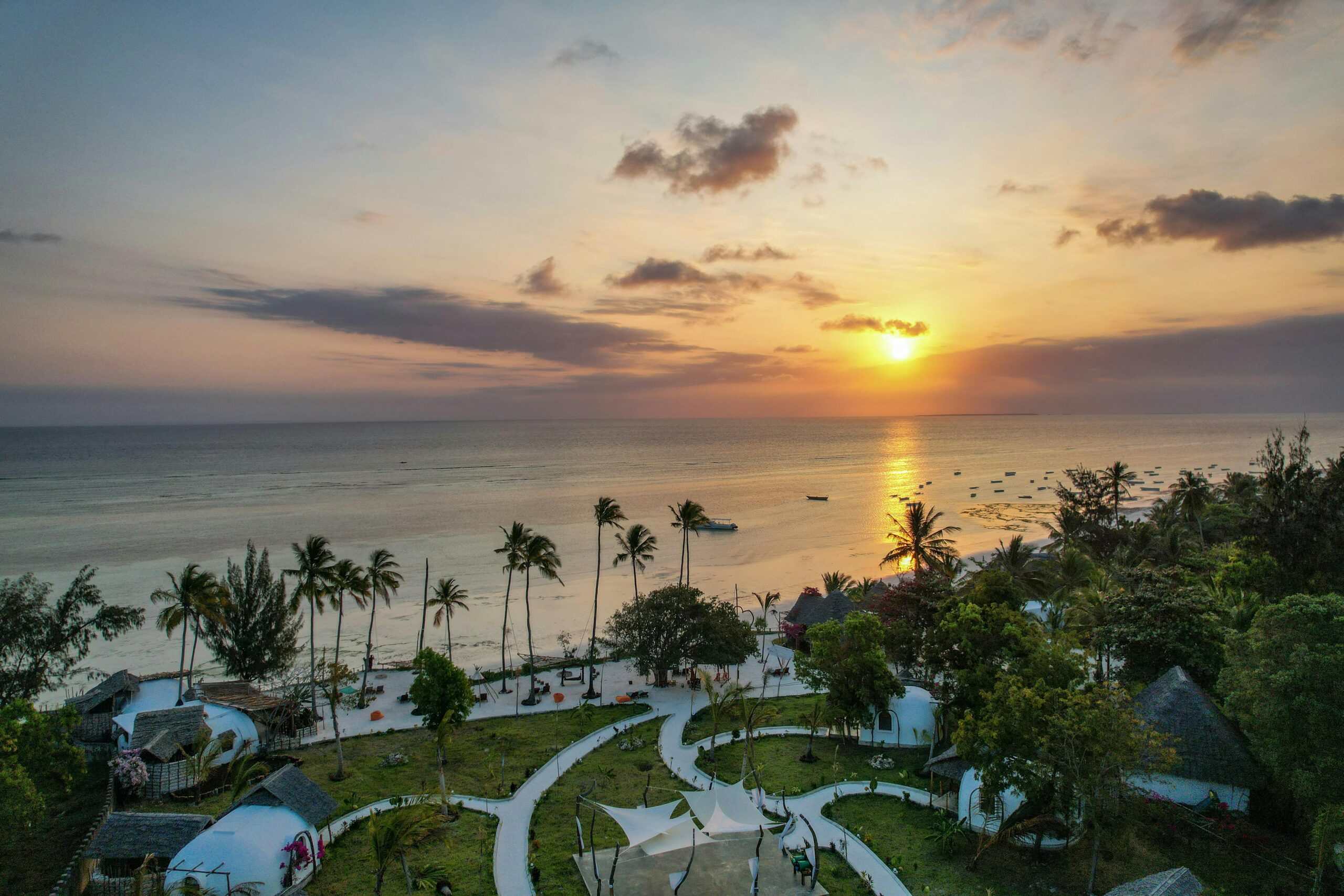 A breathtaking aerial view of Kizimkazi Beach at sunset, showcasing vibrant skies and serene waters in Tanzania.